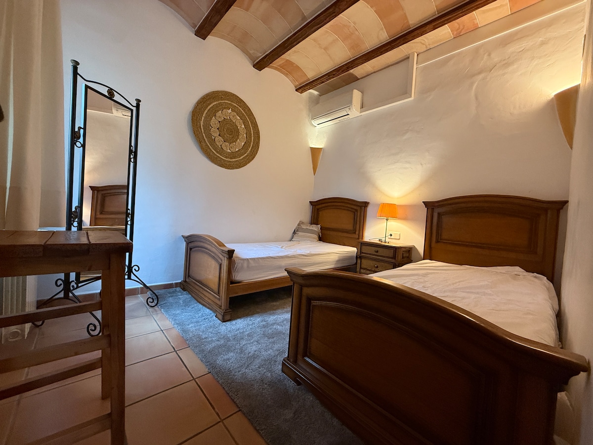 Schlafzimmer mit zwei Holz-Einzelbetten, Spiegel und Gewölbedecke