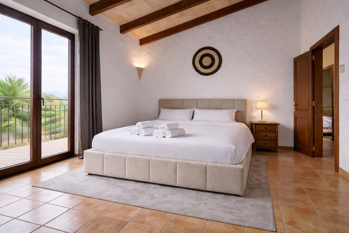 Schlafzimmer im Turm der Finca Es Castell mit Doppelbett und Blick ins Grüne