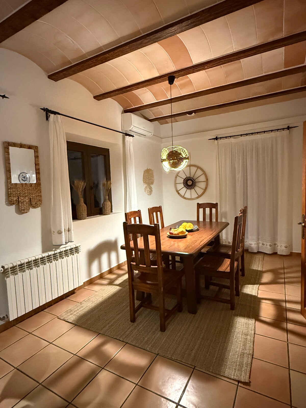 Esszimmer mit Holztisch und Korbleuchte im warmen Abendlicht
