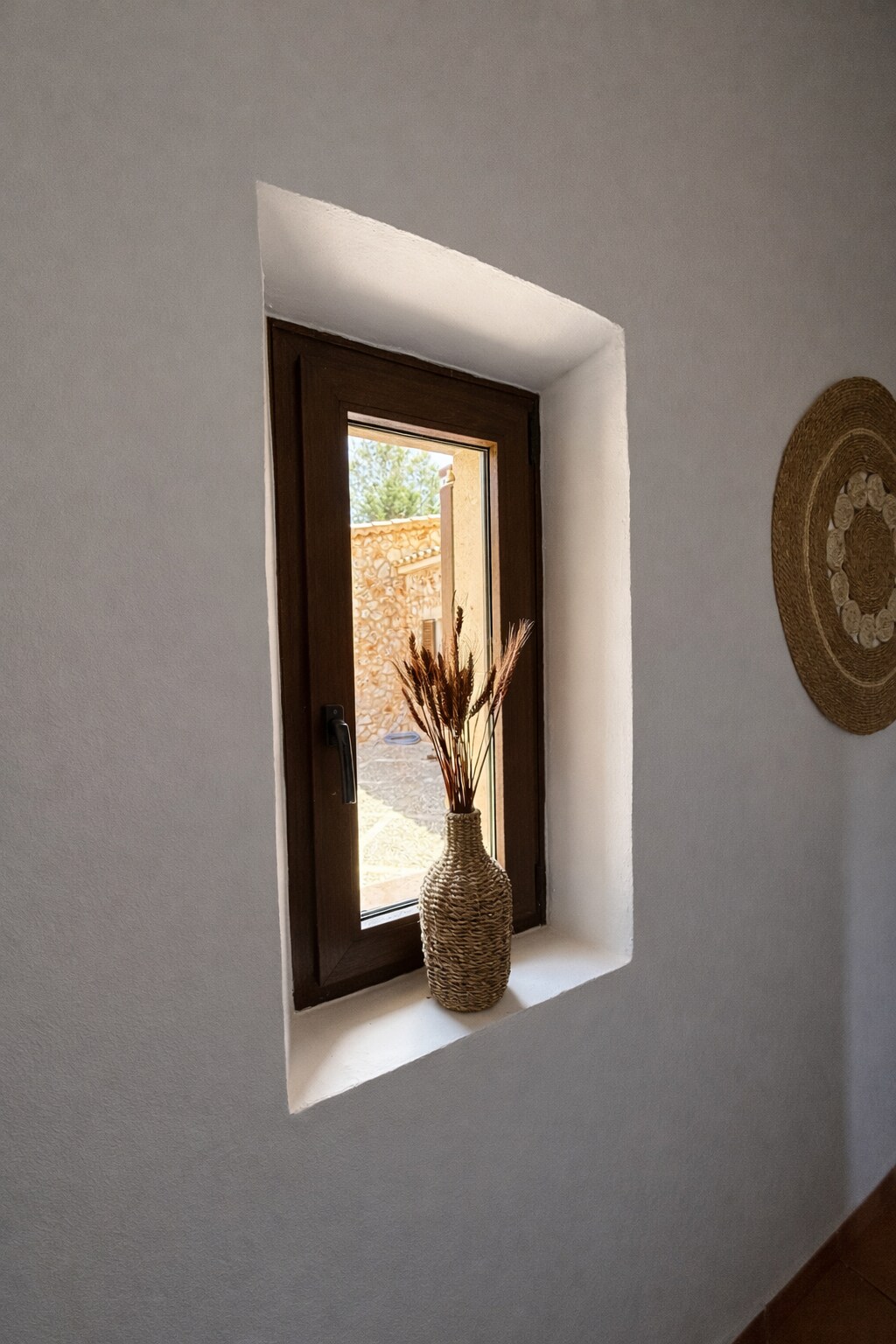 Tiefe Fensternische mit Korbvase und Trockengräsern