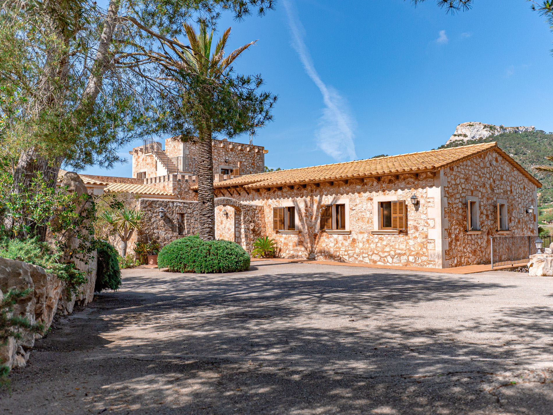Natursteinfassade der Finca Es Castell mit Palme und Bergpanorama